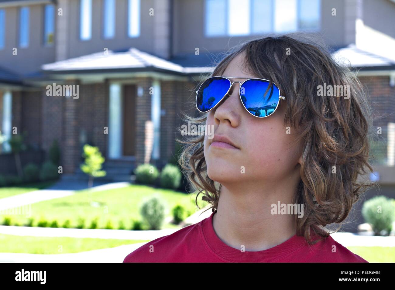 Les jeunes mâles adolescents portant des lunettes bleu head shot contre l'arrière-plan de banlieue. Banque D'Images