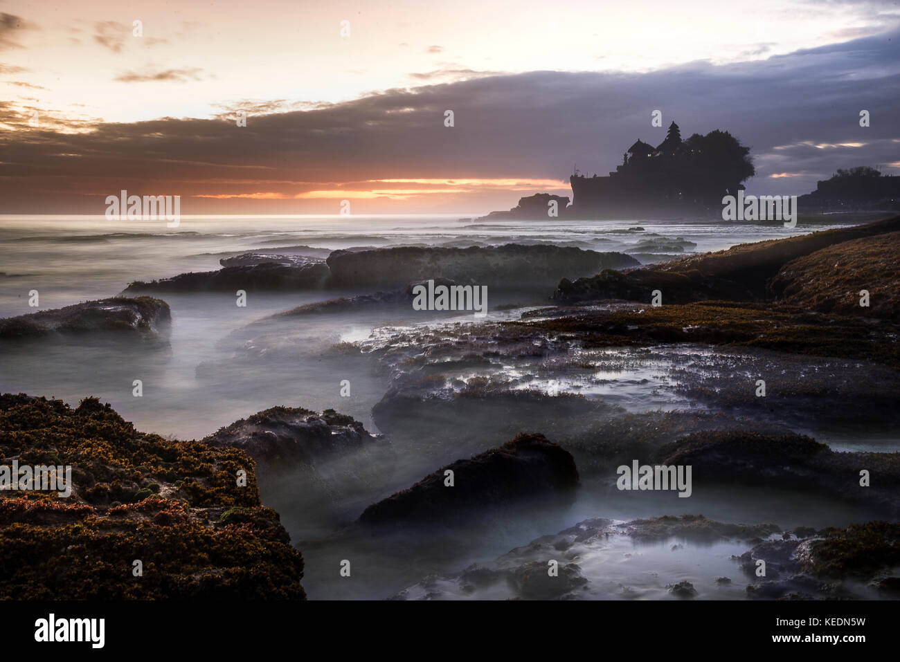 Temple de Tanah lot à Bali Indonésie au coucher du soleil et l'océan à marée basse. Banque D'Images