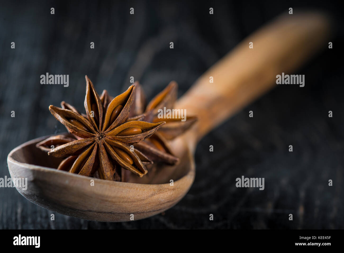 La badiane graines dans une cuillère en bois sur un backgrond noir Banque D'Images