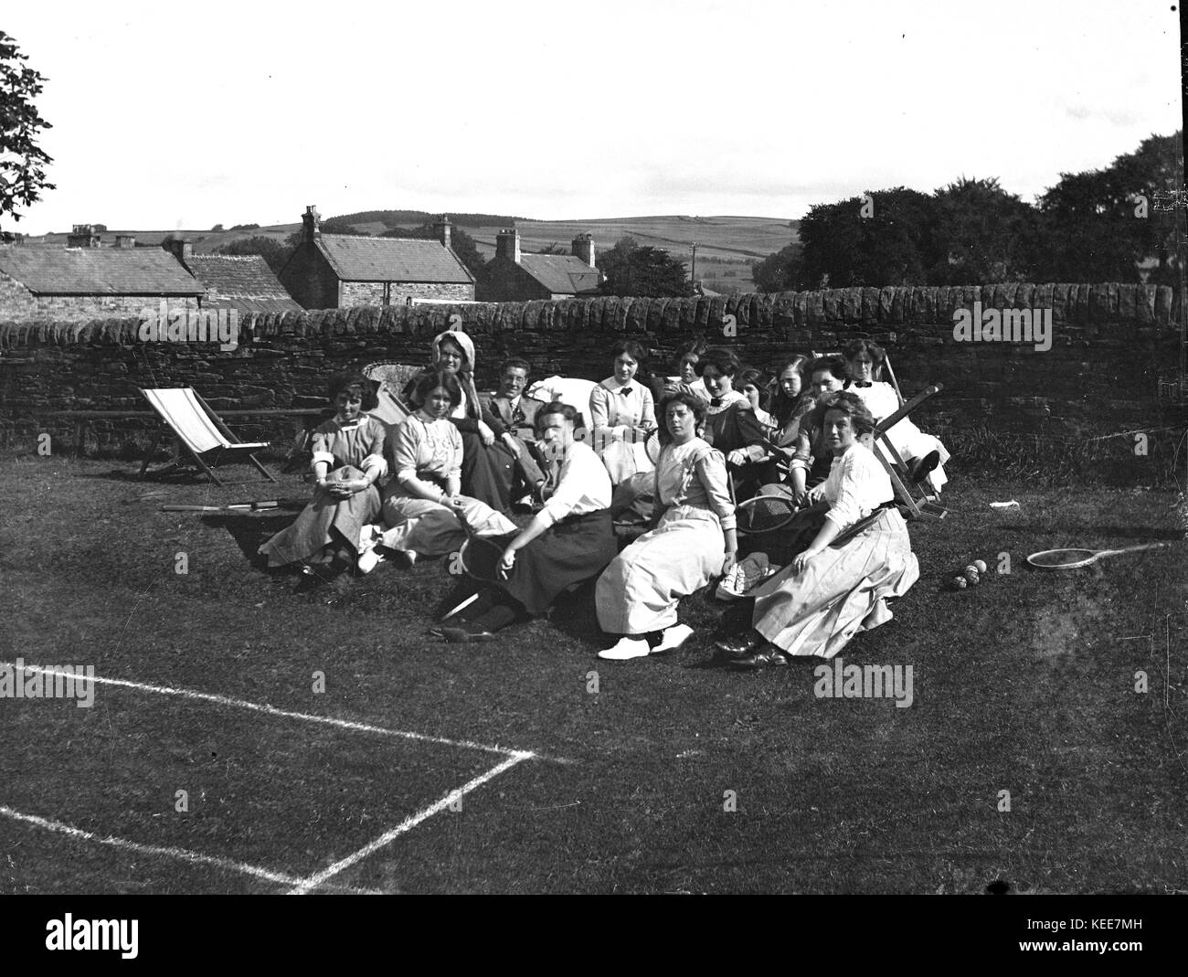 Un groupe de jeunes femmes de prendre une pause de jouer de tennis sur gazon et poser avec un homme et des femmes, allendale, Northumberland, England, 1911. Photo prise par Tony henshaw à partir de la filiale en propriété négatif original. Banque D'Images