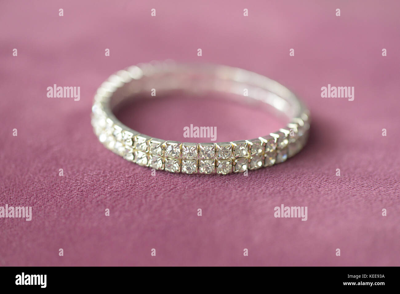 Faux diamants broche double rangée avec bracelet de montage réglage focus sélectif, positionné sur un tissu vieux rose Banque D'Images