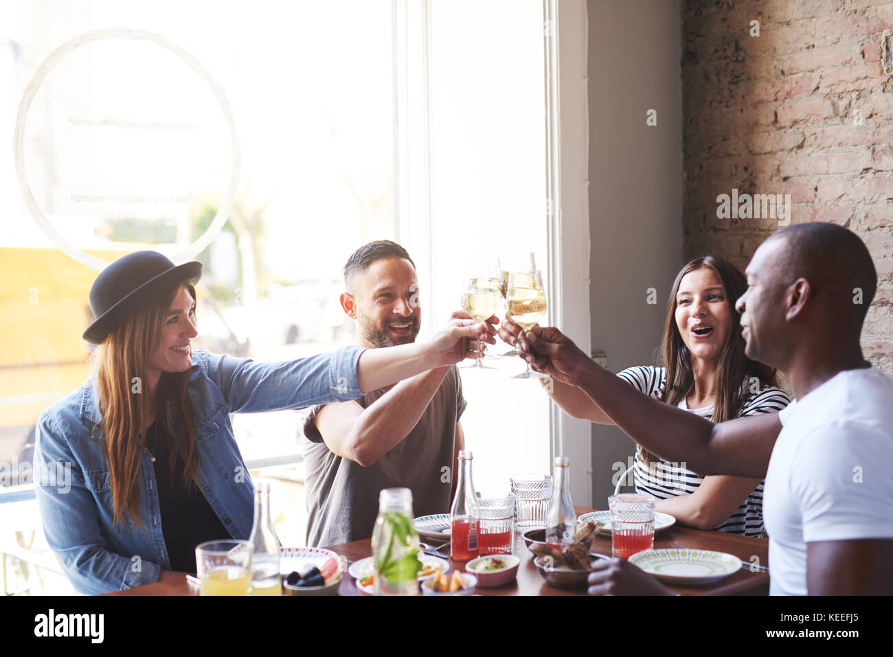 Divers Groupe de jeunes adultes mâles et femelles célébrer quelque chose ensemble avec des verres à vin à table in restaurant Banque D'Images