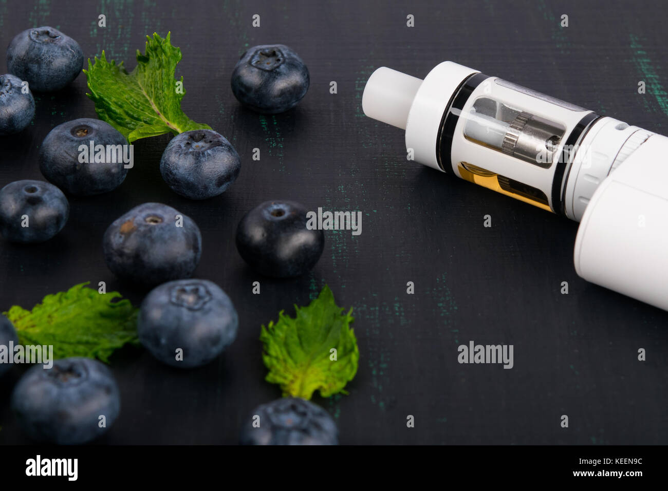 Cigarette électronique blanche sur un tableau noir, à côté d'un berry épars Banque D'Images