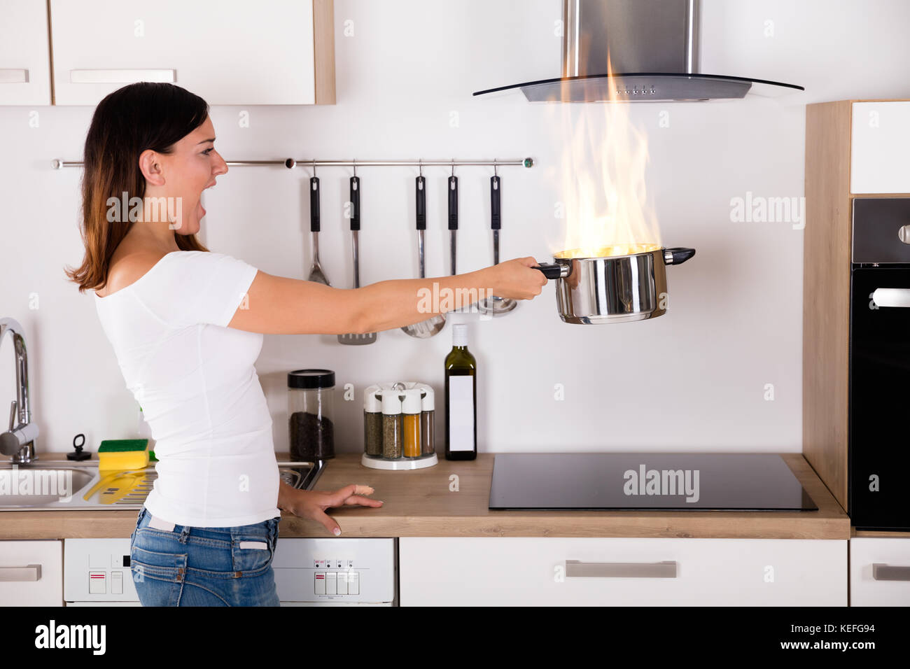 Choqué Woman Cooking pot au feu près de gaz dans la cuisine moderne Banque D'Images