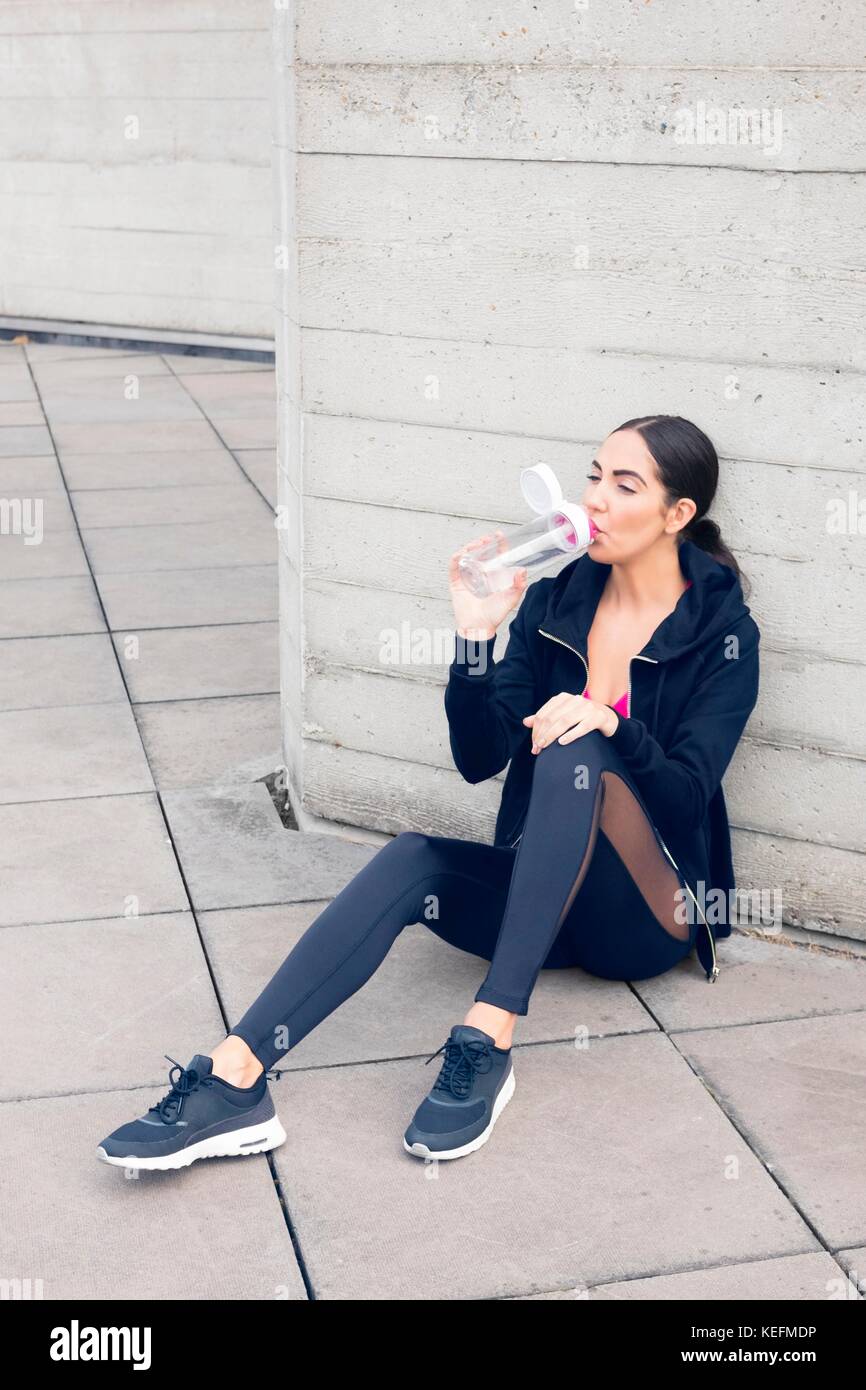 Parution du modèle. Jeune femme assise sur le plancher de l'eau potable. Banque D'Images