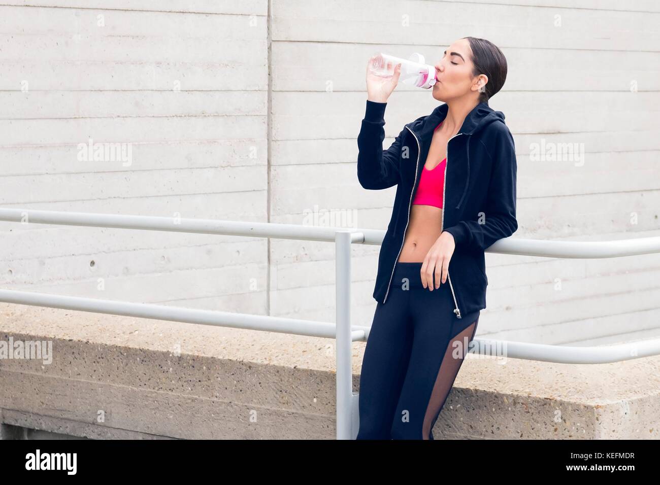 Parution du modèle. Jeune femme debout par la construction d'eau potable. Banque D'Images