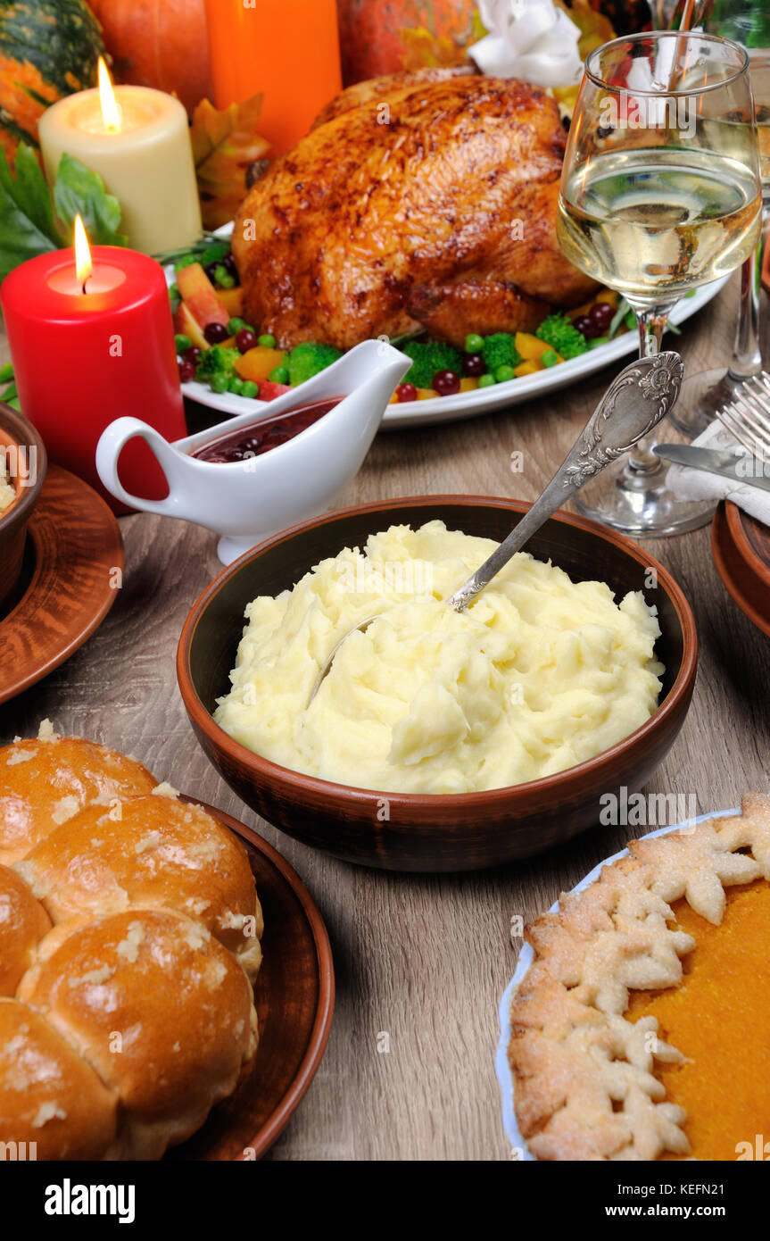 Un bol de purée de pommes de terre sur une table entre la tarte à la citrouille cuite, Turquie, cranberry-sauce à l'orange, un verre de vin blanc pour Thanksgiving Banque D'Images