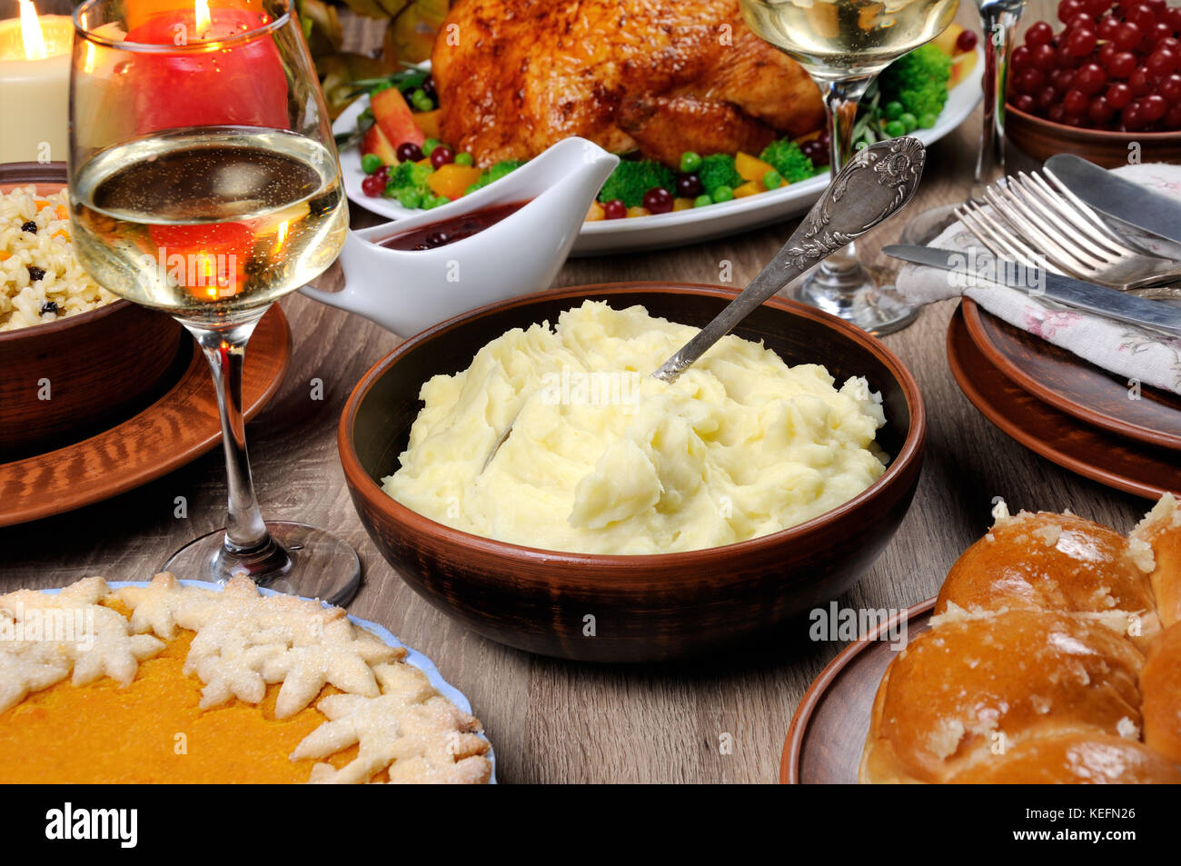 Un bol de purée de pommes de terre sur une table entre la tarte à la citrouille cuite, Turquie, cranberry-sauce à l'orange, un verre de vin blanc pour Thanksgiving Banque D'Images