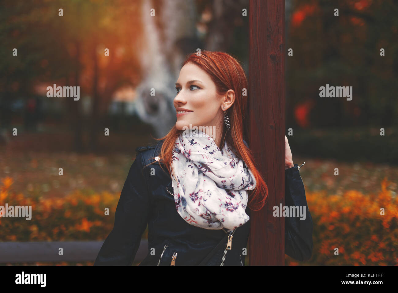 Jeune femme rousse branché à la voiture en stationnement à l'automne Banque D'Images