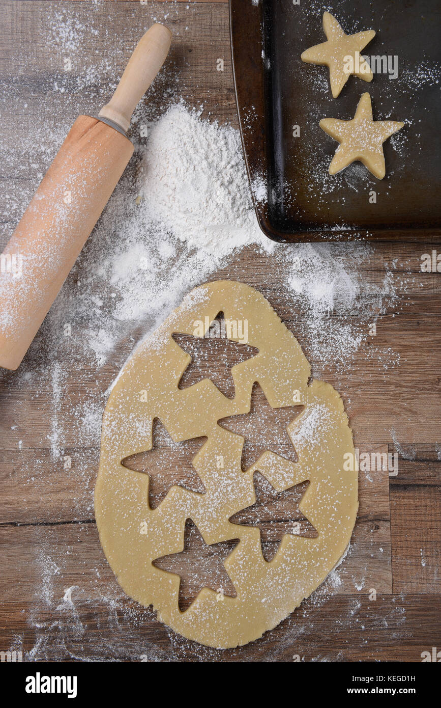 Vue de dessus de la pâte à biscuits avec star formes et de l'emporte-pièce sur la table de bois avec un rouleau à pâtisserie et saupoudrer de farine et de biscuits. Banque D'Images