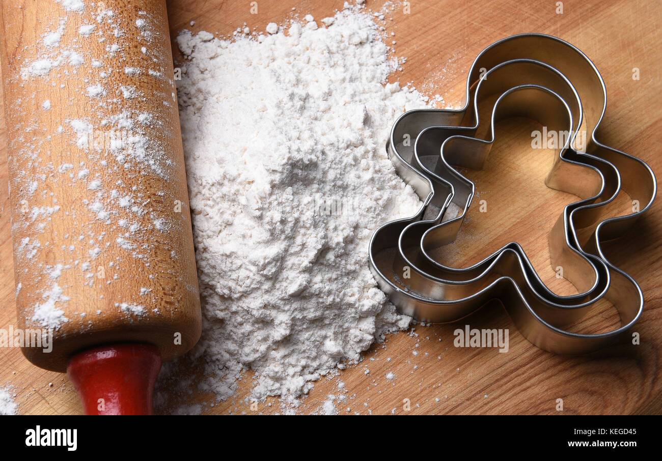 Vue de dessus gros plan d'un rouleau à pâtisserie sur une planche à découper, la farine et le gingerbread man emporte-pièce. Banque D'Images