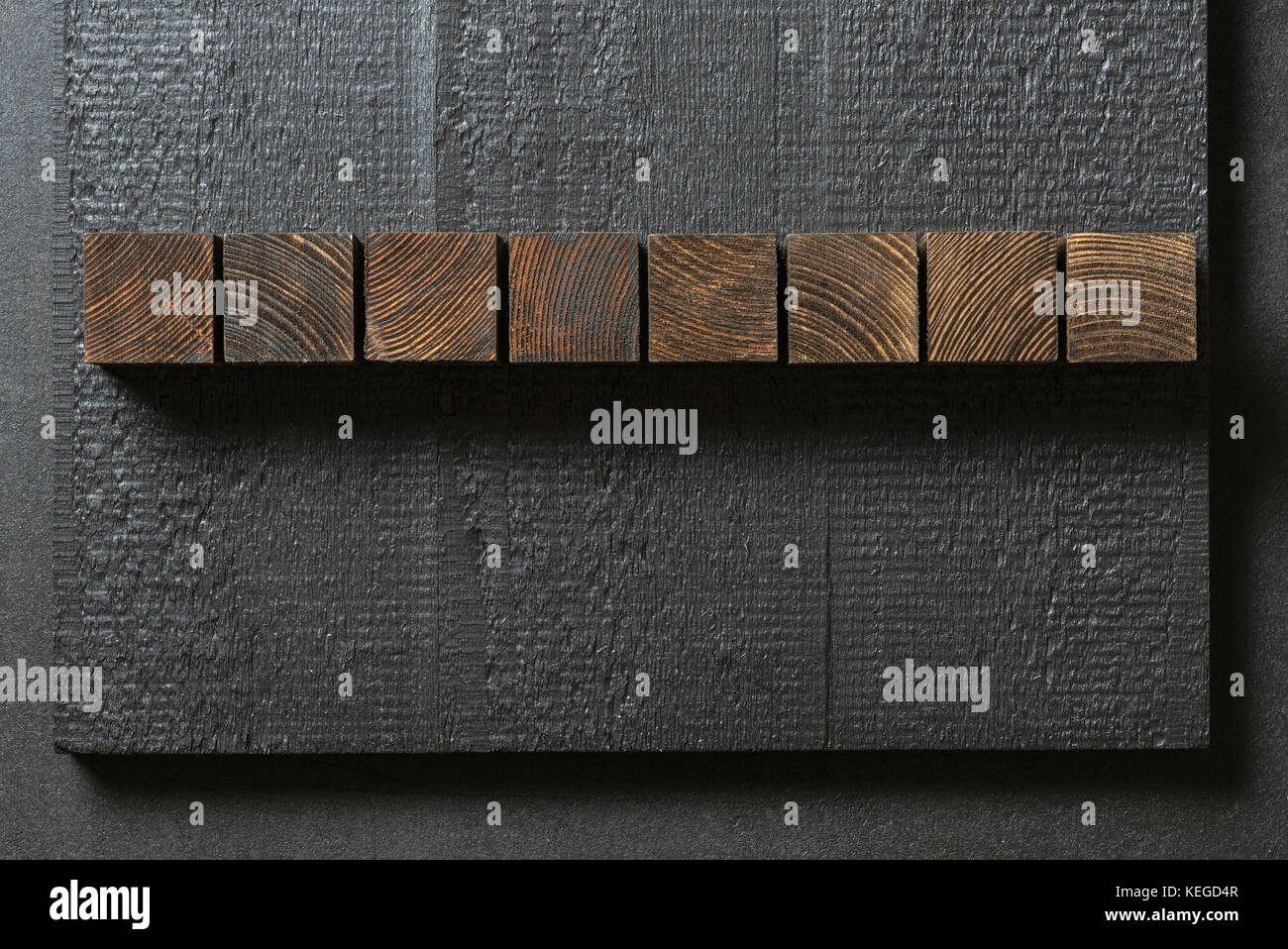 Blocs de bois brun foncé sur noir charpente rugueux. Les cubes peuvent être utilisés pour des lettres. Banque D'Images