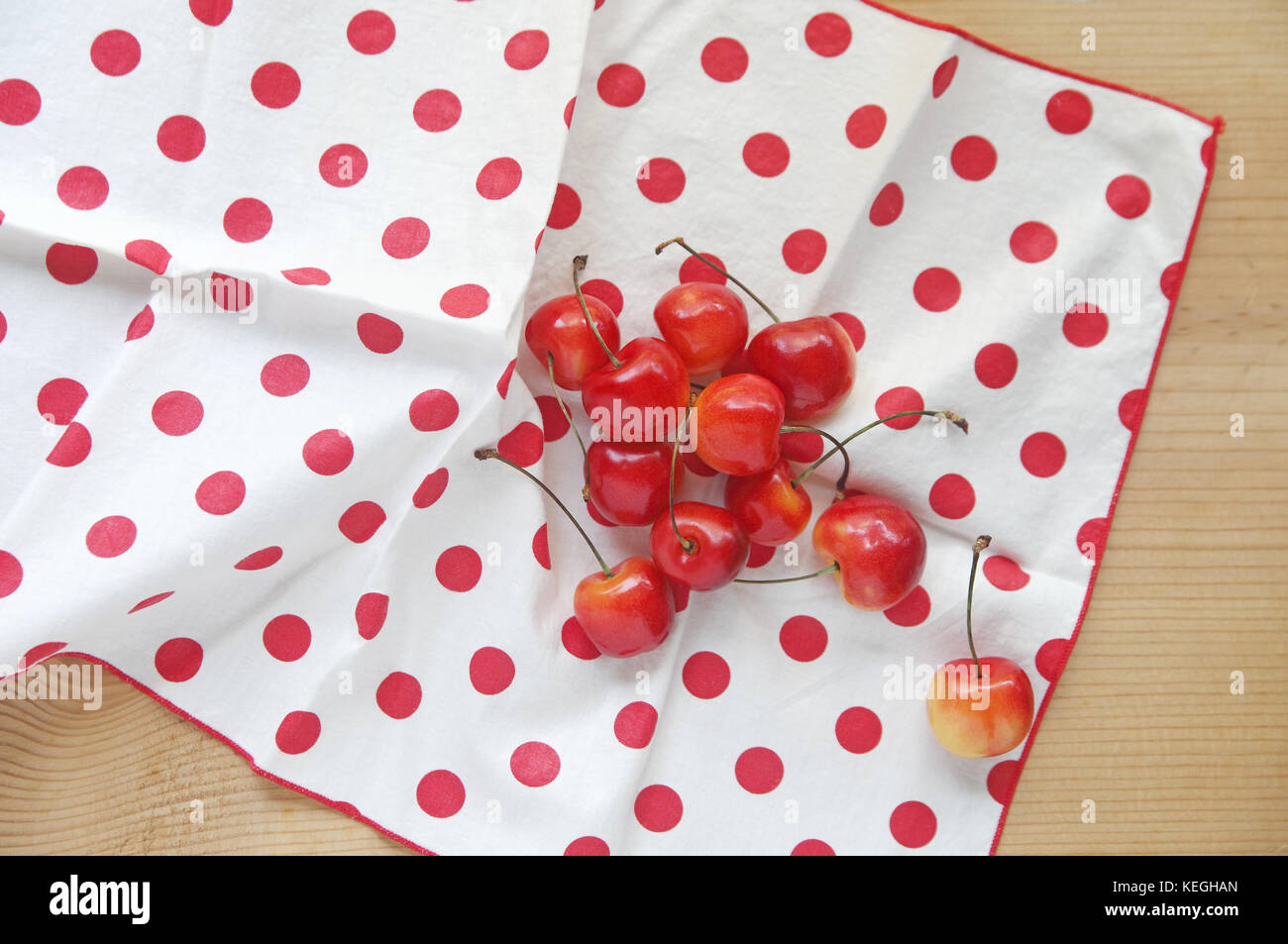 Cerises fraîches sur une serviette blanche à pois rouges Banque D'Images