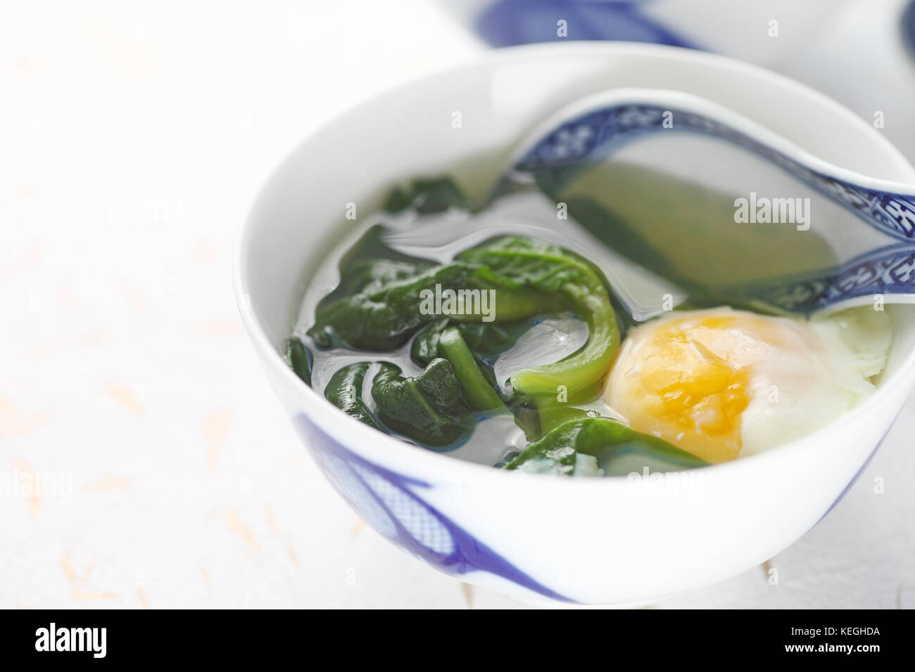 Soupe d'épinard malabar avec œuf poché en chinois bol avec cuillère et copy space Banque D'Images