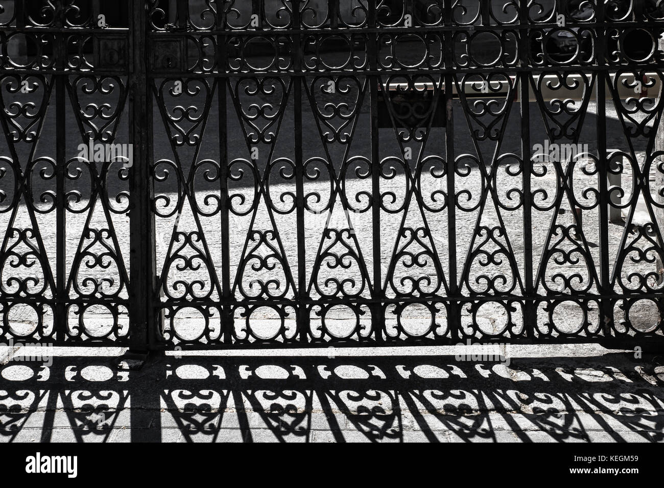 Porte en fer forgé avec des bars et des ombres sur le trottoir Banque D'Images