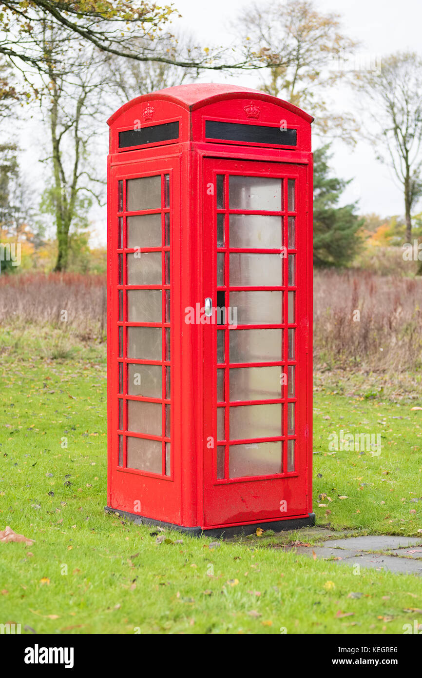 Vieux téléphone rouge fort seul dans l'isolement rural on Green grass Banque D'Images