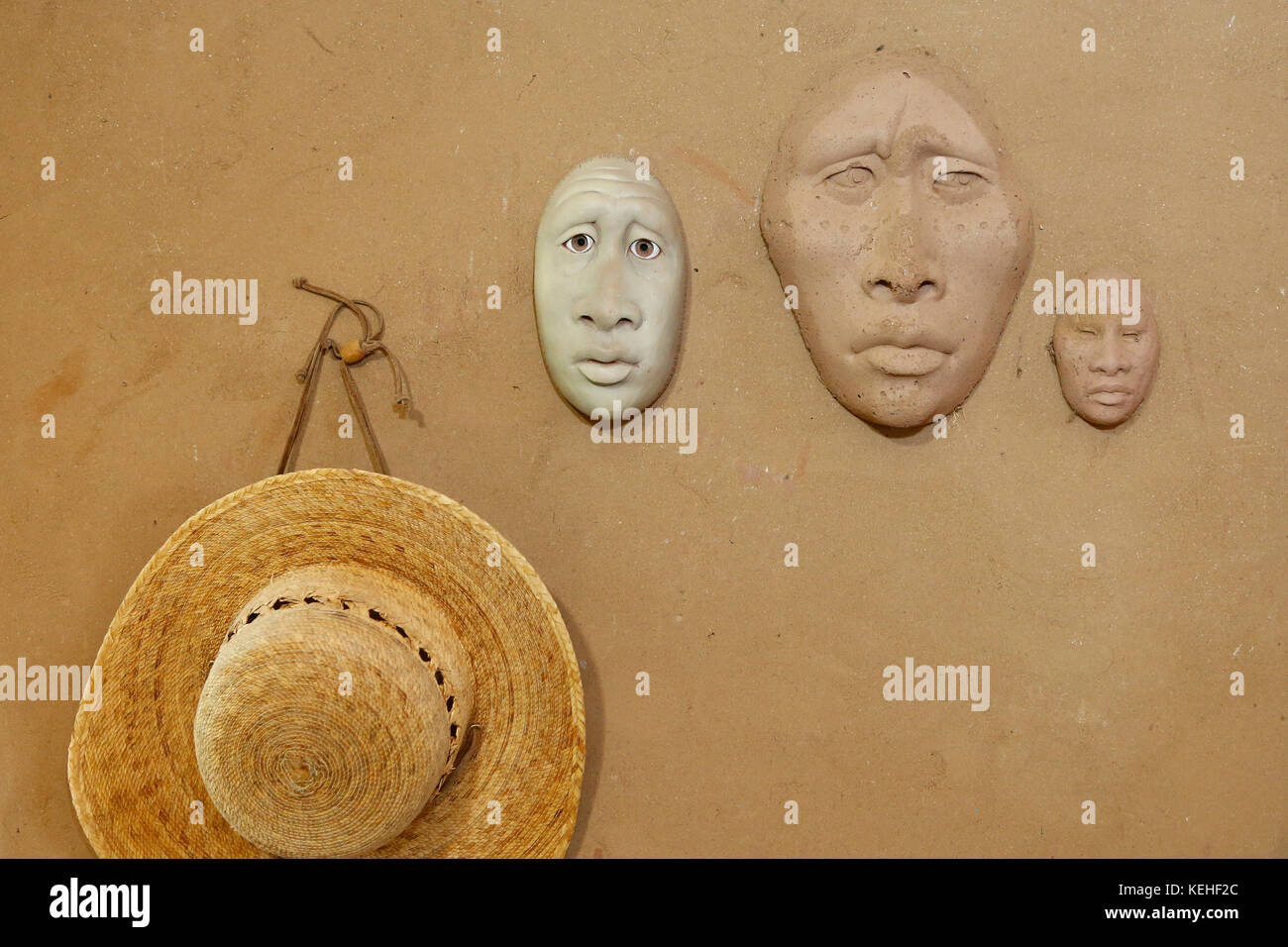 Masques en argile et chapeau accrochés au mur Banque D'Images