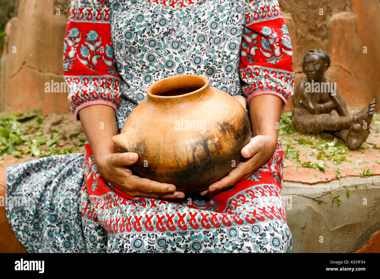 Femme assise et tenant pot d'argile Banque D'Images