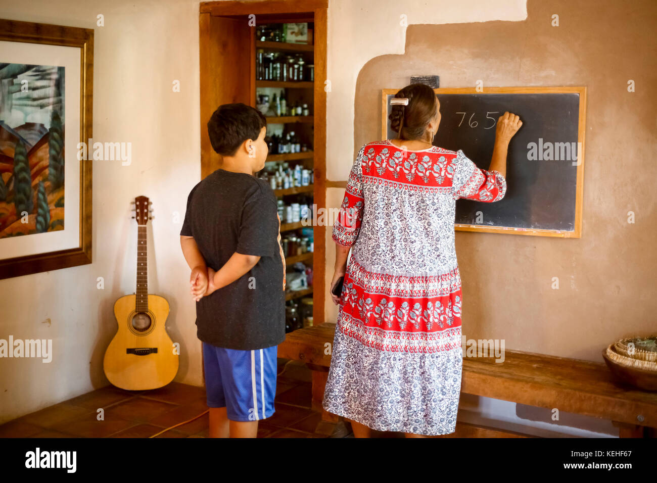 Femme écrivant l'équation sur le tableau noir pour son fils Banque D'Images