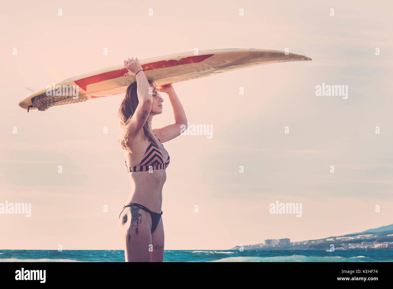 Caucasian woman standing on beach with surfboard on Banque D'Images
