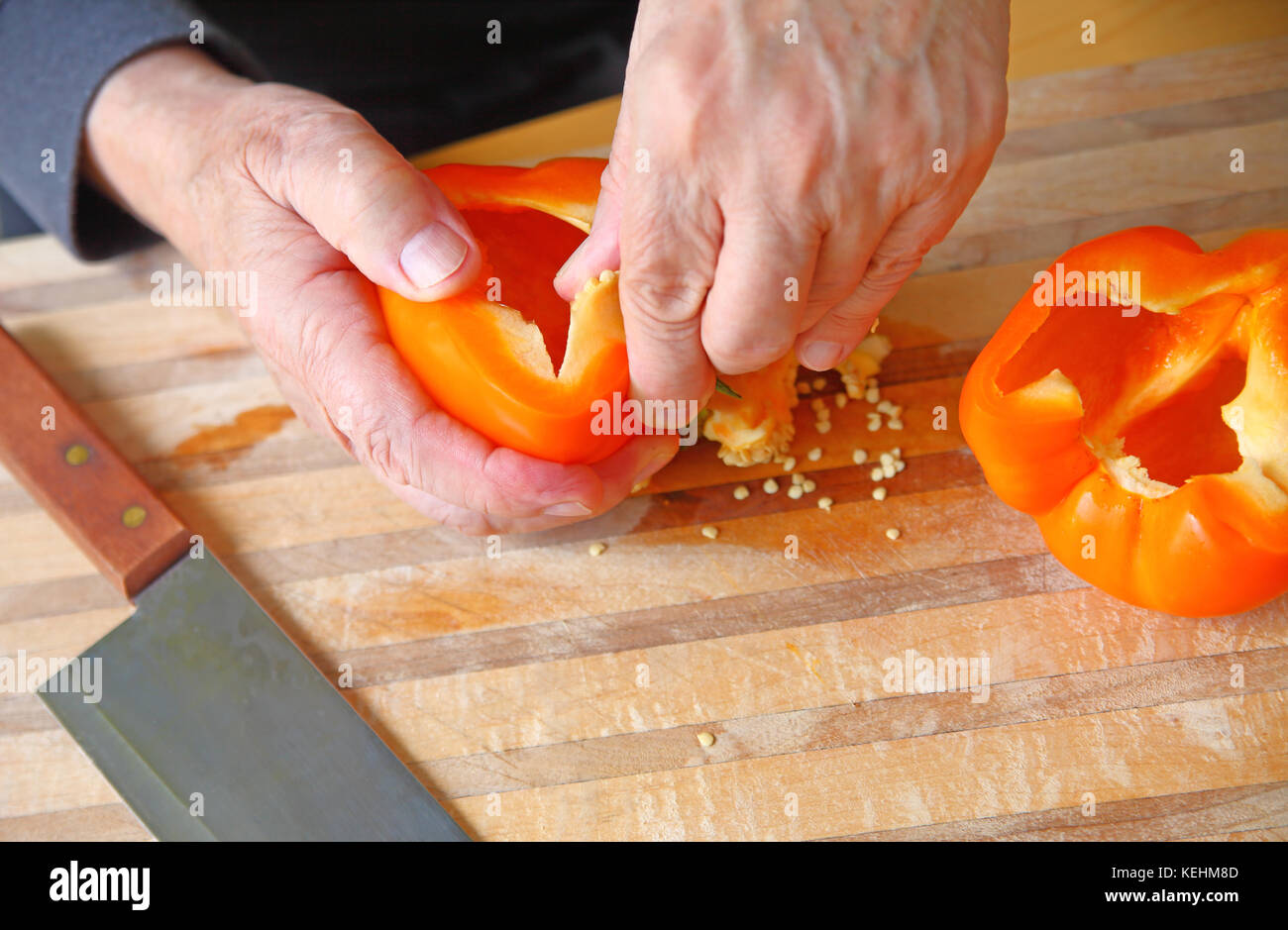 Un homme enlève des semences d'un poivron orange avec place pour le texte Banque D'Images