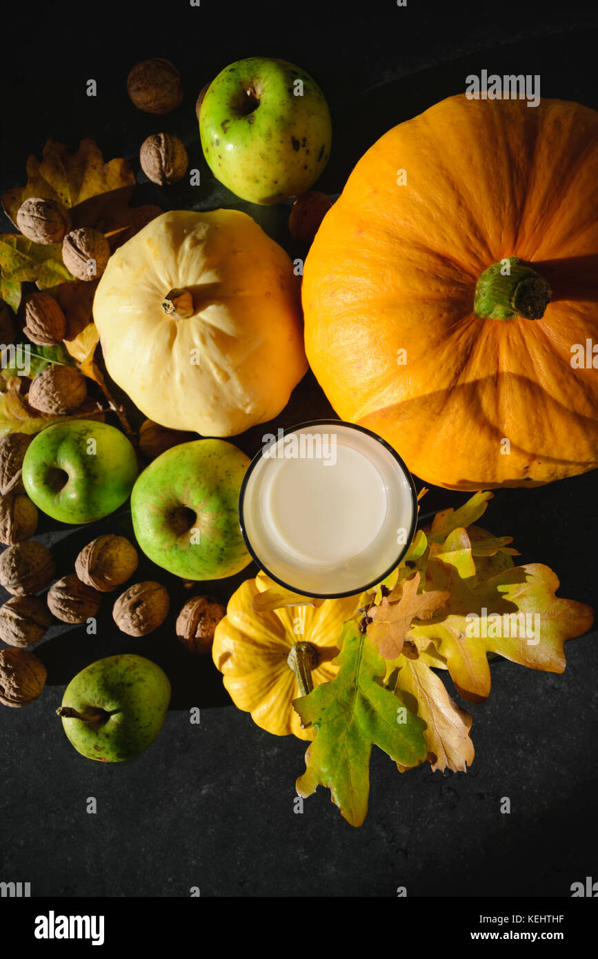 Citrouilles orange et jaune, vert pomme, la ferme et les écrous de la paroi d'un verre de lait de vache sur la table maikng embient encore une belle composition d'automne de la vie Banque D'Images