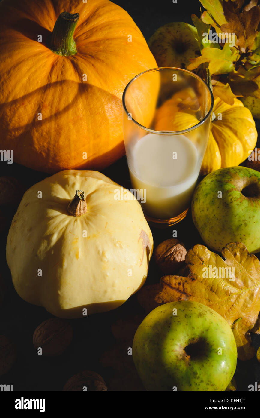 Citrouilles orange et jaune, vert pomme, la ferme et les écrous de la paroi d'un verre de lait de vache sur la table maikng embient encore une belle composition d'automne de la vie Banque D'Images
