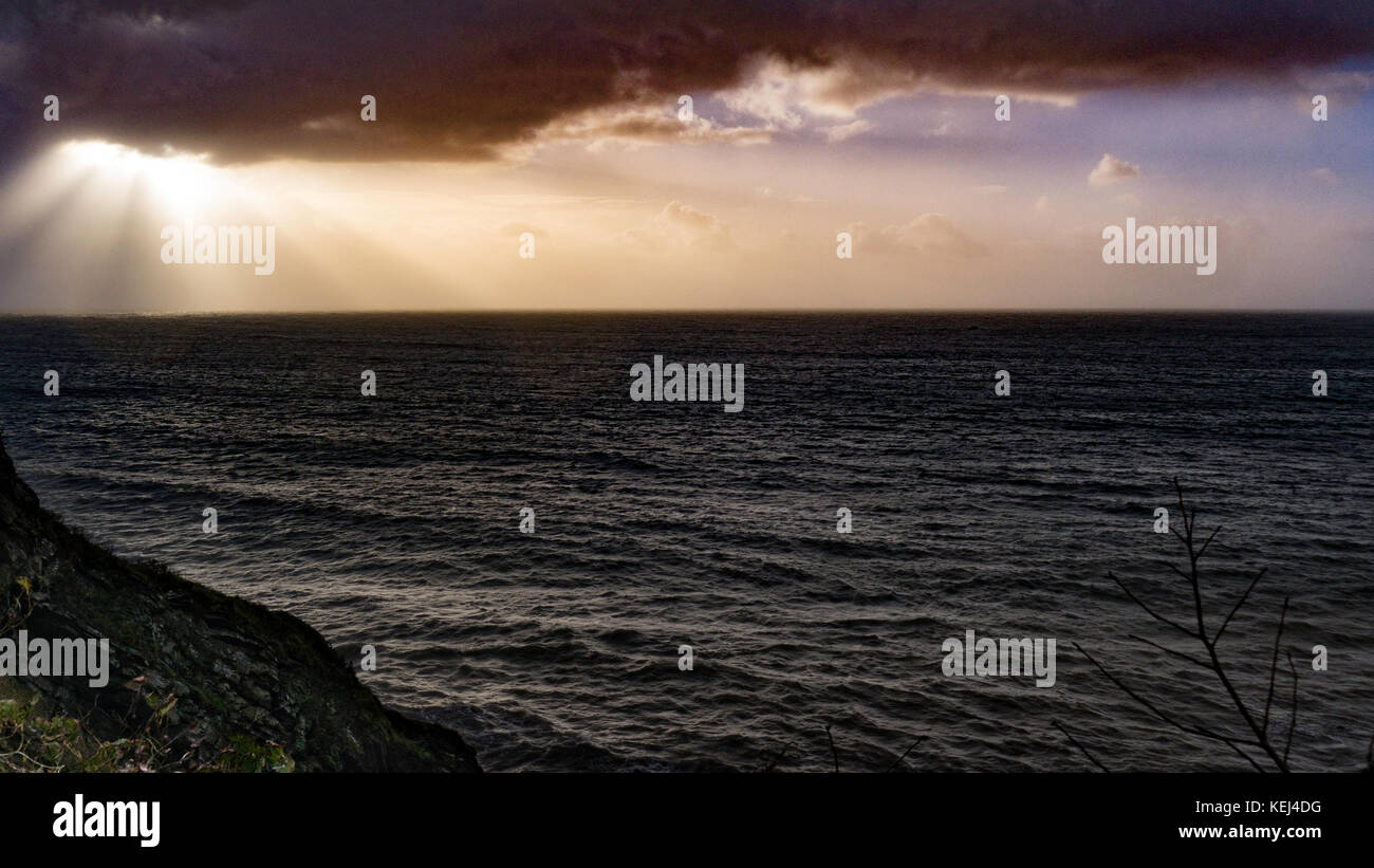 La lumière du soleil se brise à travers les nuages lourds. Vue spectaculaire sur la côte tôt le matin, alors que la tempête atlantique Brian atteint le sud de Cornwall, au Royaume-Uni Banque D'Images