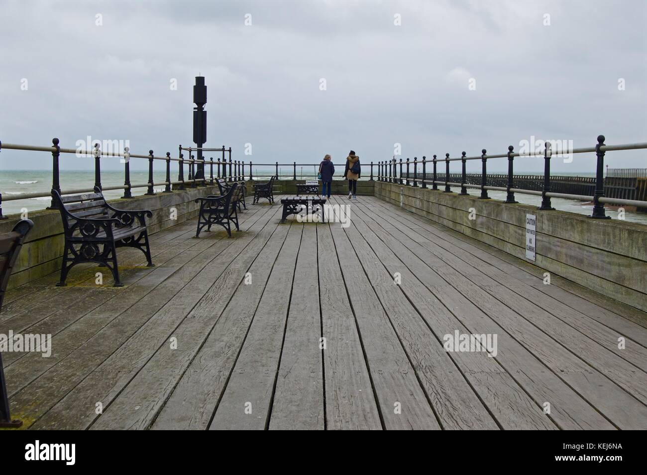 Femme noir et blanc femme marche sur jetty, Littlehampton, Royaume-Uni Banque D'Images