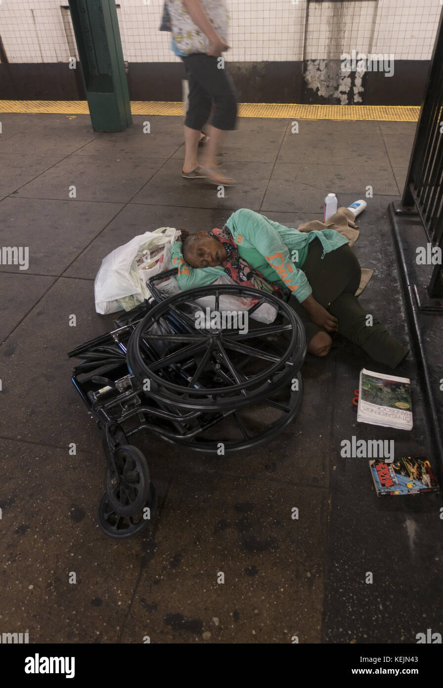 Apparemment sans abri double amputée dort par son fauteuil roulant écrasé sur la plate-forme de métro de la station de métro West 4th Street à Greenwich Village, New York City. Banque D'Images