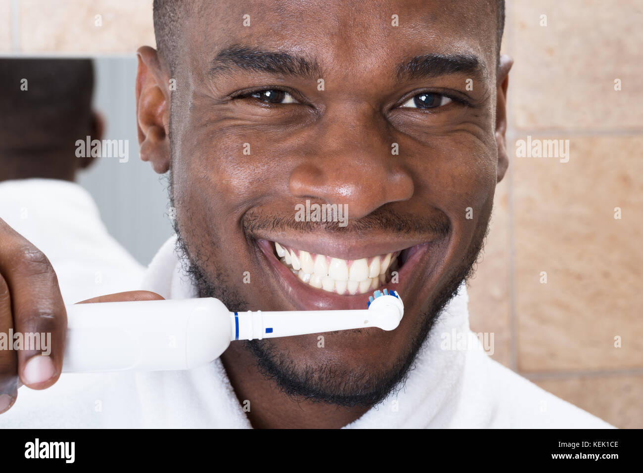 Heureux homme africain le nettoyage des dents avec une brosse à dents in  front of mirror Photo Stock - Alamy
