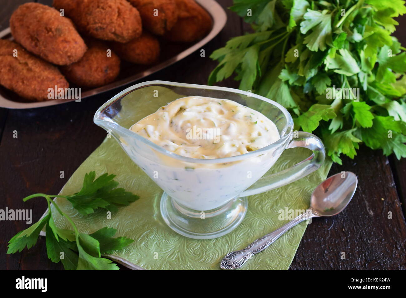 Sauce Tartare pour les plats de poisson avec du yogourt, les câpres, l'ail et le citron, l'huile d'olive et le sucre dans une saucière en verre sur un fond de bois foncé. Manger sain Banque D'Images