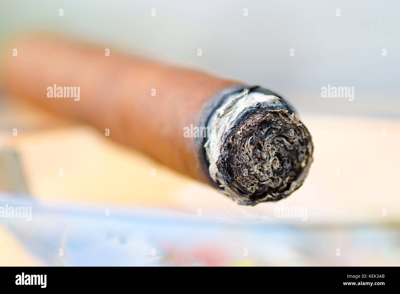 Photo en gros plan d'un cigare dans un cendrier en verre avec un arrière-plan flou Banque D'Images