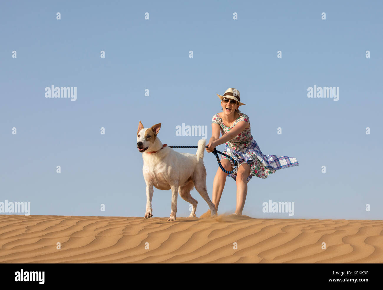 Jeune femme avec un chien errant dans un désert Banque D'Images