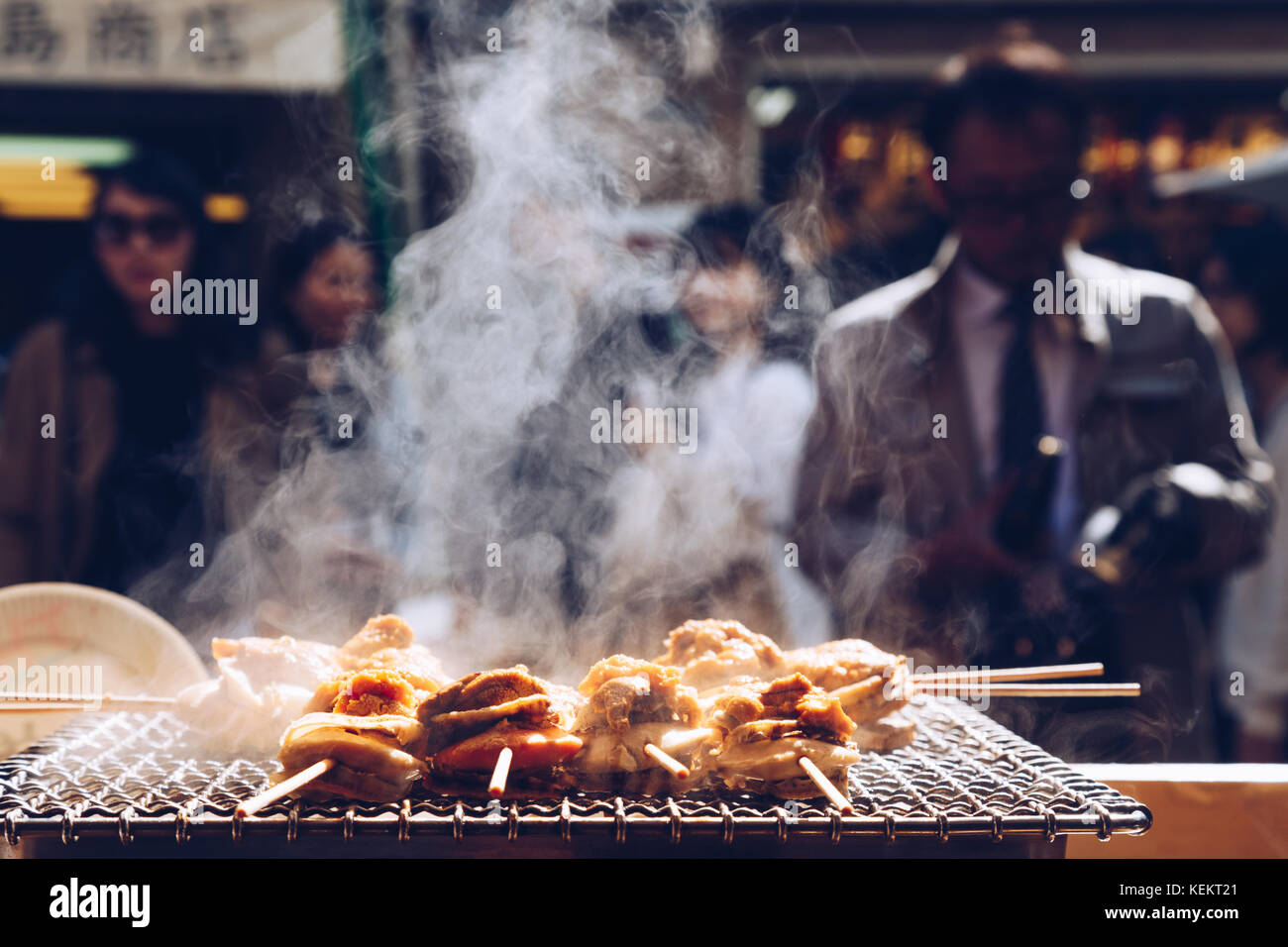 Fruits de mer grillés et de pétoncles mer ​​Urchin oeufs broche avec la fumée, de l'alimentation de rue japonais au marché aux poissons de Tsukiji, Japon. focus sélectif et insert. Banque D'Images