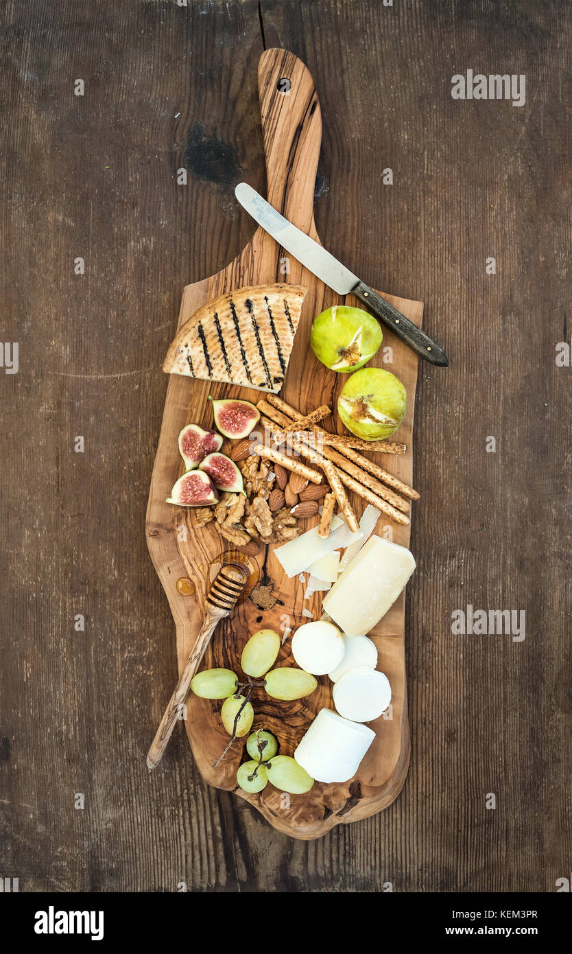 Hors-d'vin set : sélection de fromages, miel, raisins, amandes, noix, pain, figs sur bois olive servant au fond rustique , top vi Banque D'Images