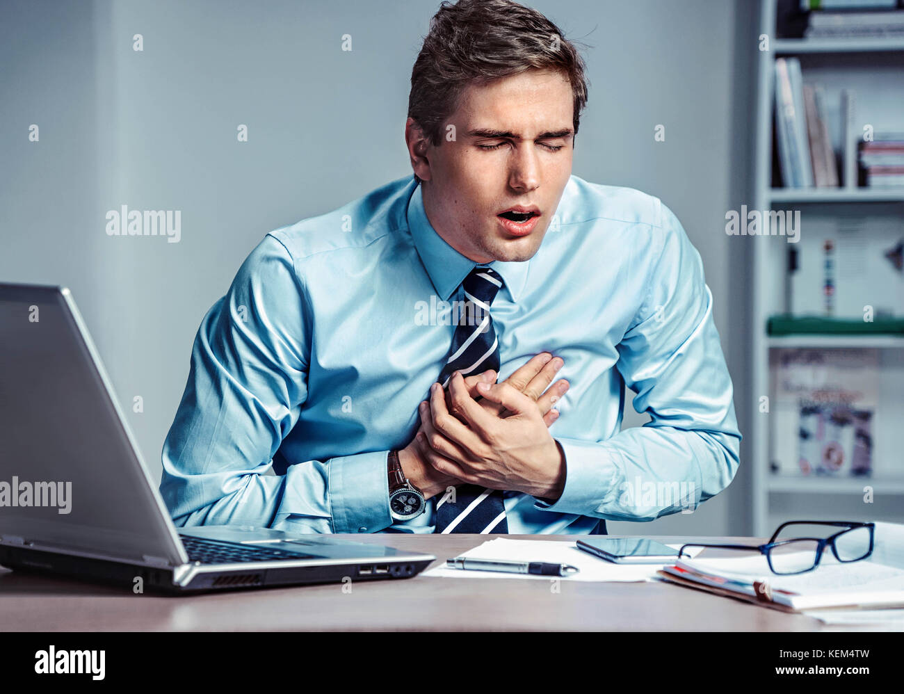 Office manager d'avoir une crise cardiaque. photo de jeune homme tenant la main sur la poitrine douloureuse sur le lieu de travail. concept médical. Banque D'Images