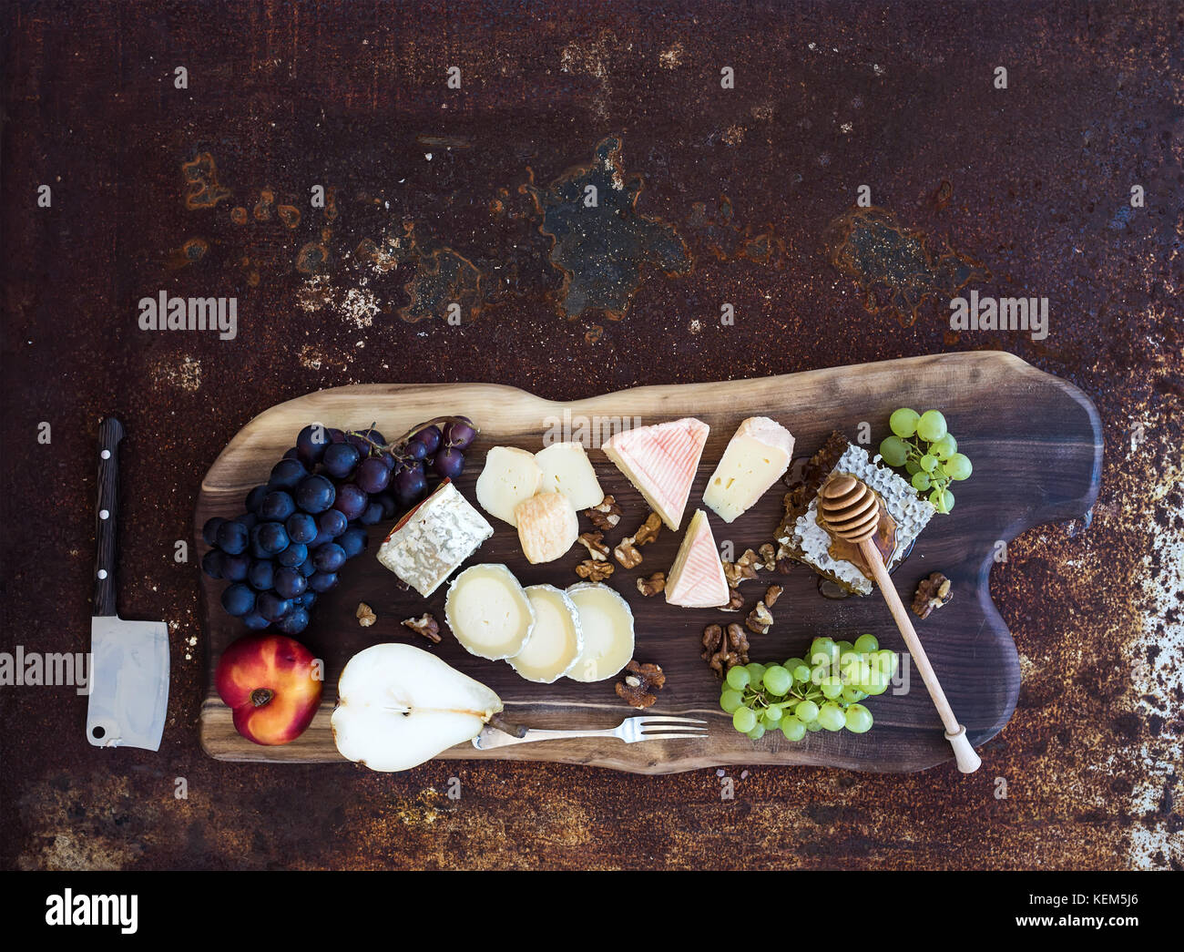 Hors-d'vin set : sélection de fromages français, de miel, de raisin, de pêche et de noix sur planche de bois rustique sur dark grunge metal background. Vue de dessus Banque D'Images