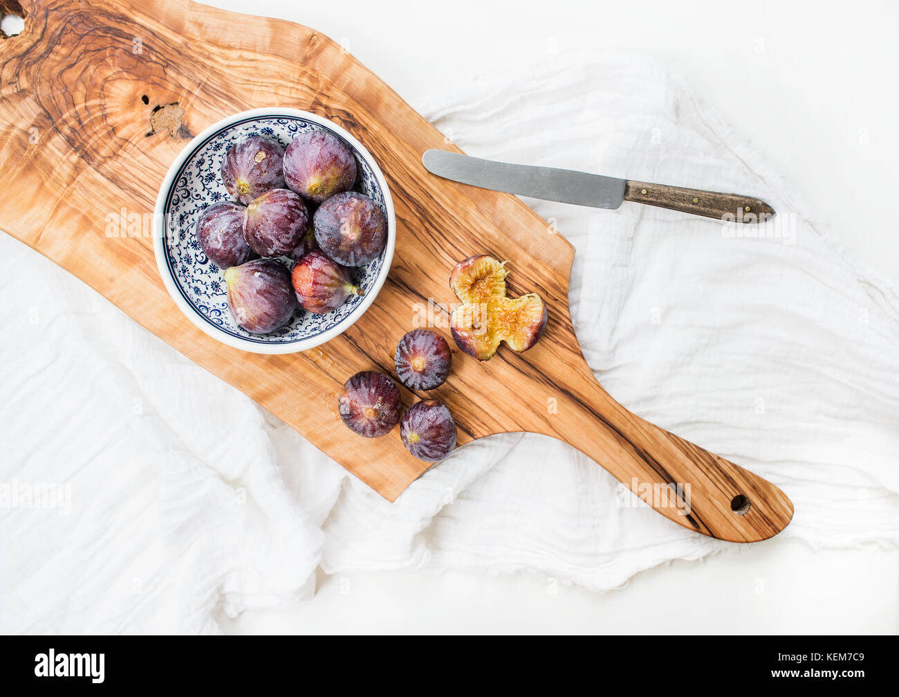 Figues fraîches en bleu Bol en céramique à motifs et sur bois d'olive sur fond blanc Banque D'Images