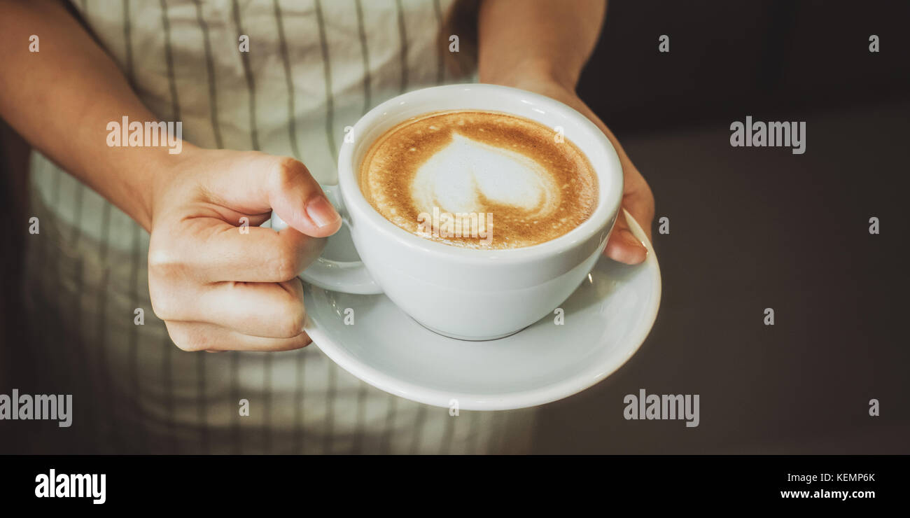 Close-up part d'une serveuse de servir une tasse de café au client. focus sélectif. Banque D'Images