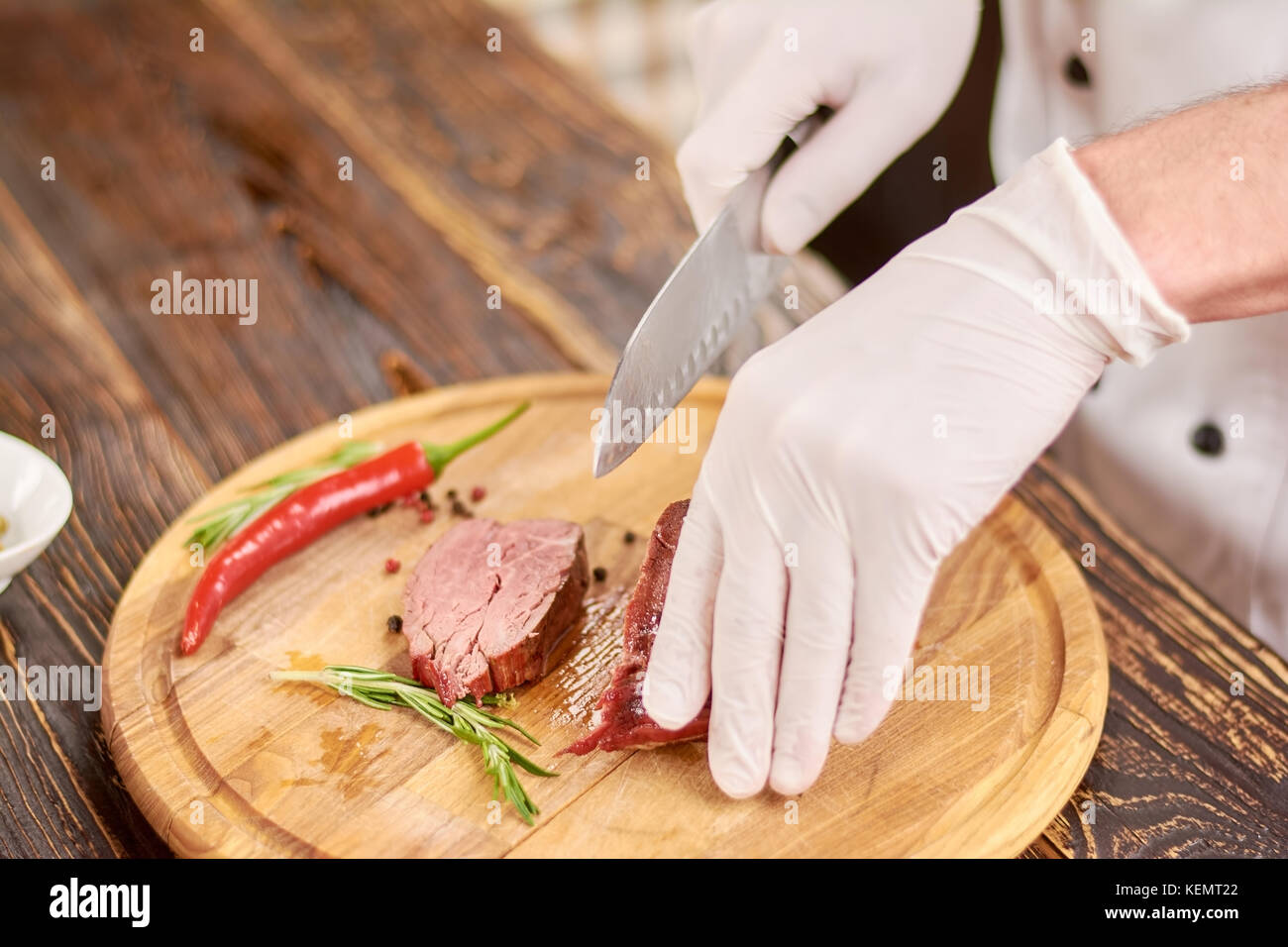Couteau chef part avec pavé de boeuf à hacher les mains. faire cuire un steak de boeuf grillé appétissant sur planche de bois. au travail, chef de cuisine. Banque D'Images