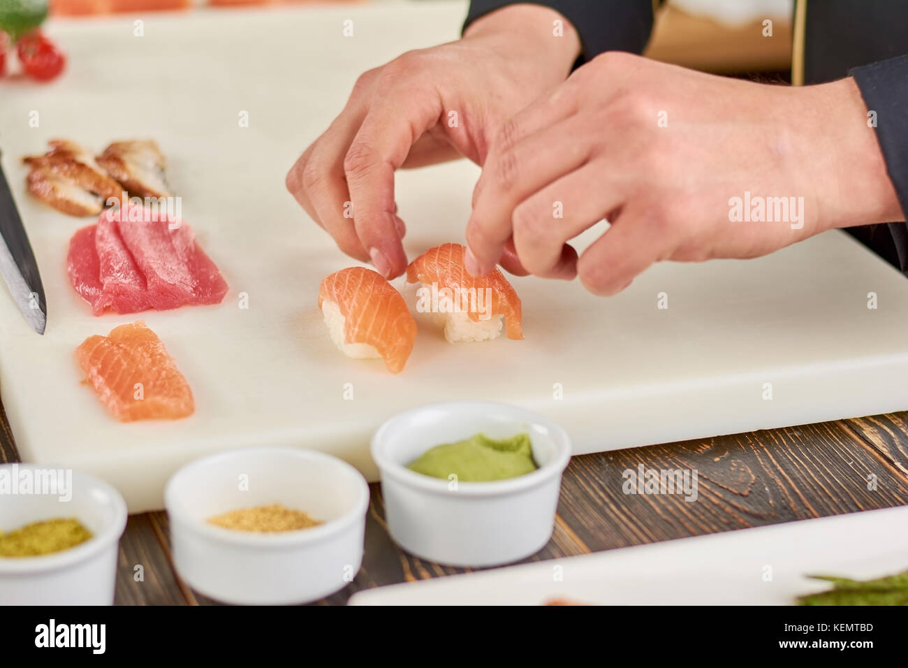 Chef mains cuisine nigiri sushi. male chef mains préparation de sushi nigiri au saumon sur tableau blanc. le processus de fabrication de sushis. Banque D'Images