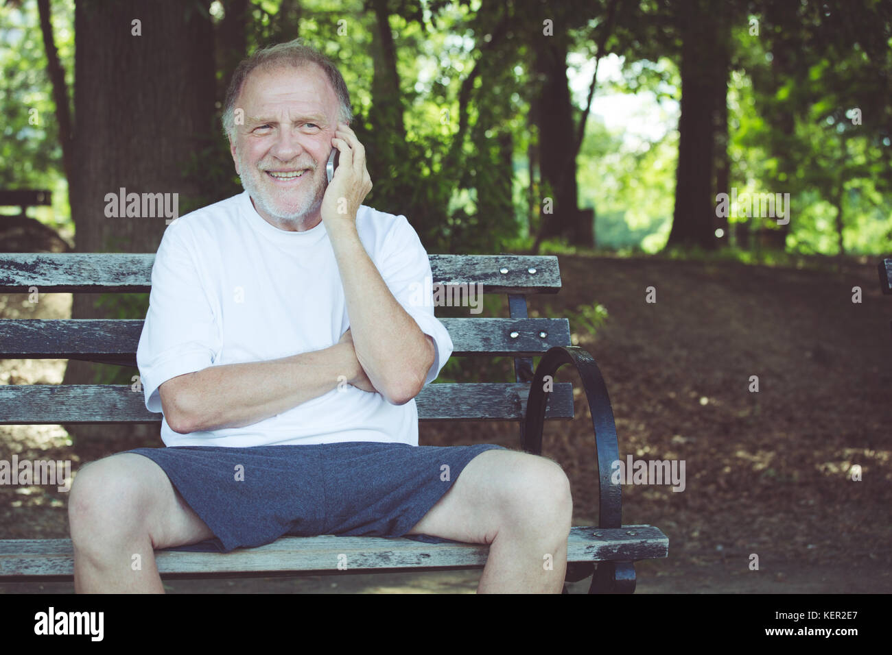 Closeup portrait, plus heureux, ravis man sitting on bench talking on cell phone, isolé à l'extérieur contexte Banque D'Images