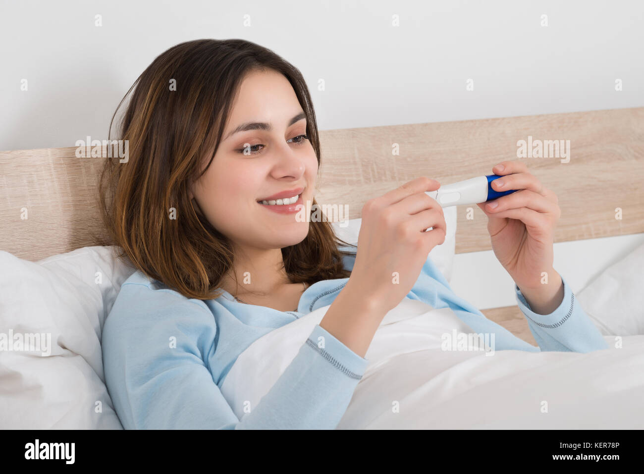 Happy young woman checking test de grossesse sur son lit Banque D'Images