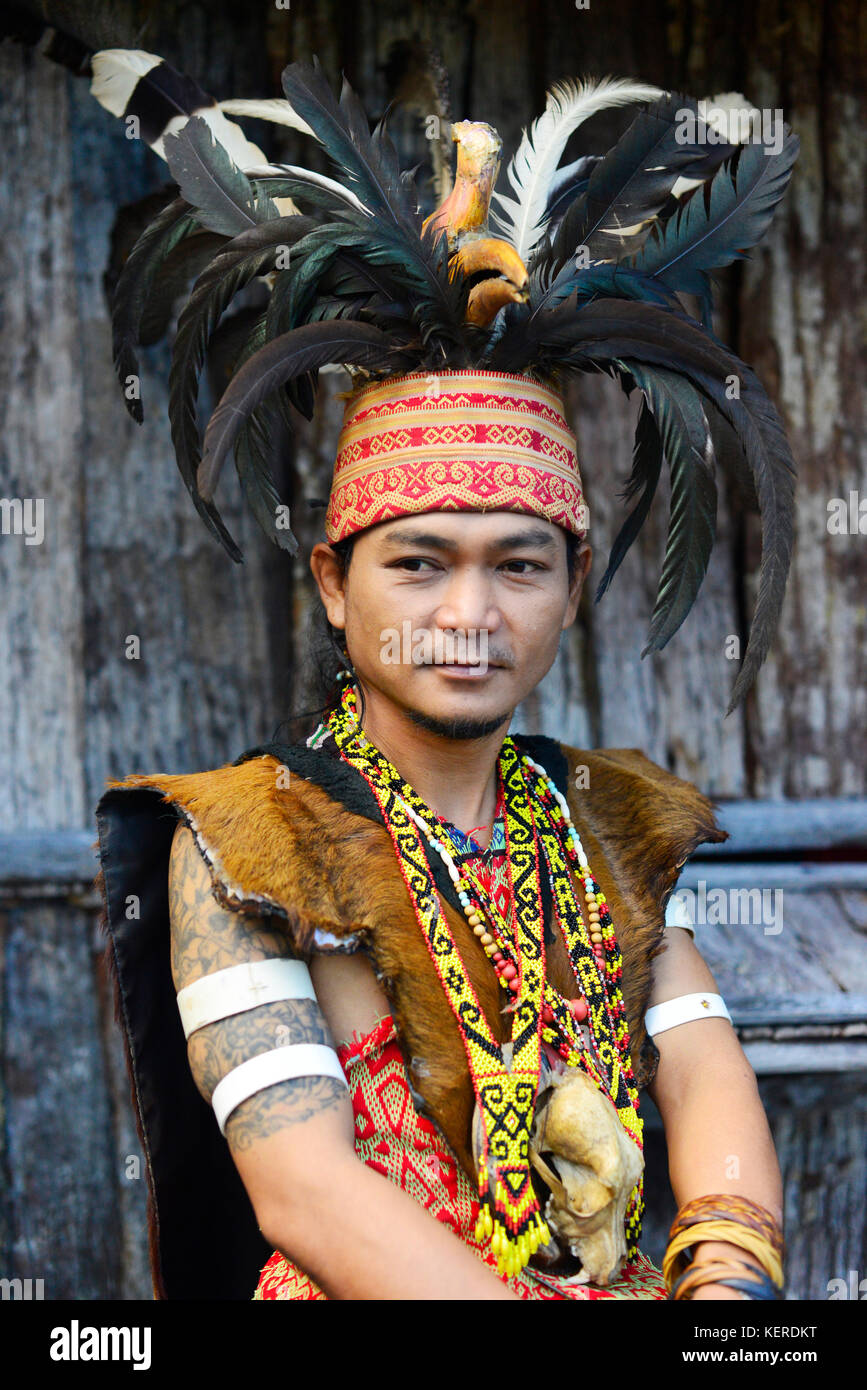 Un jeune homme à l'iban headhunter guerrier regalia, y compris la coiffure de plumes calao, au village culturel de Sarawak. Banque D'Images
