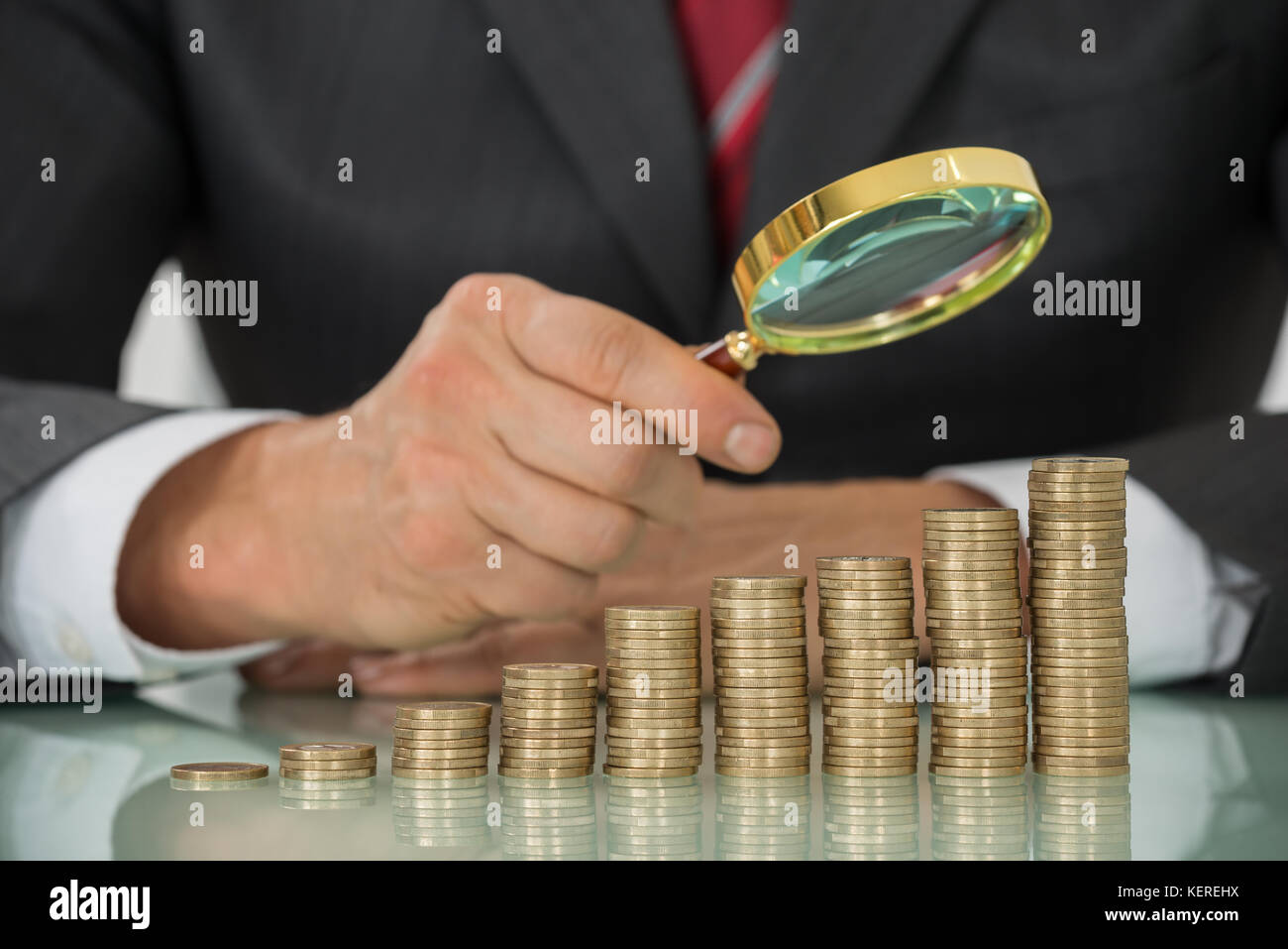 Close-up of businessman hand holding loupe sur pièce de monnaie à 24 Banque D'Images
