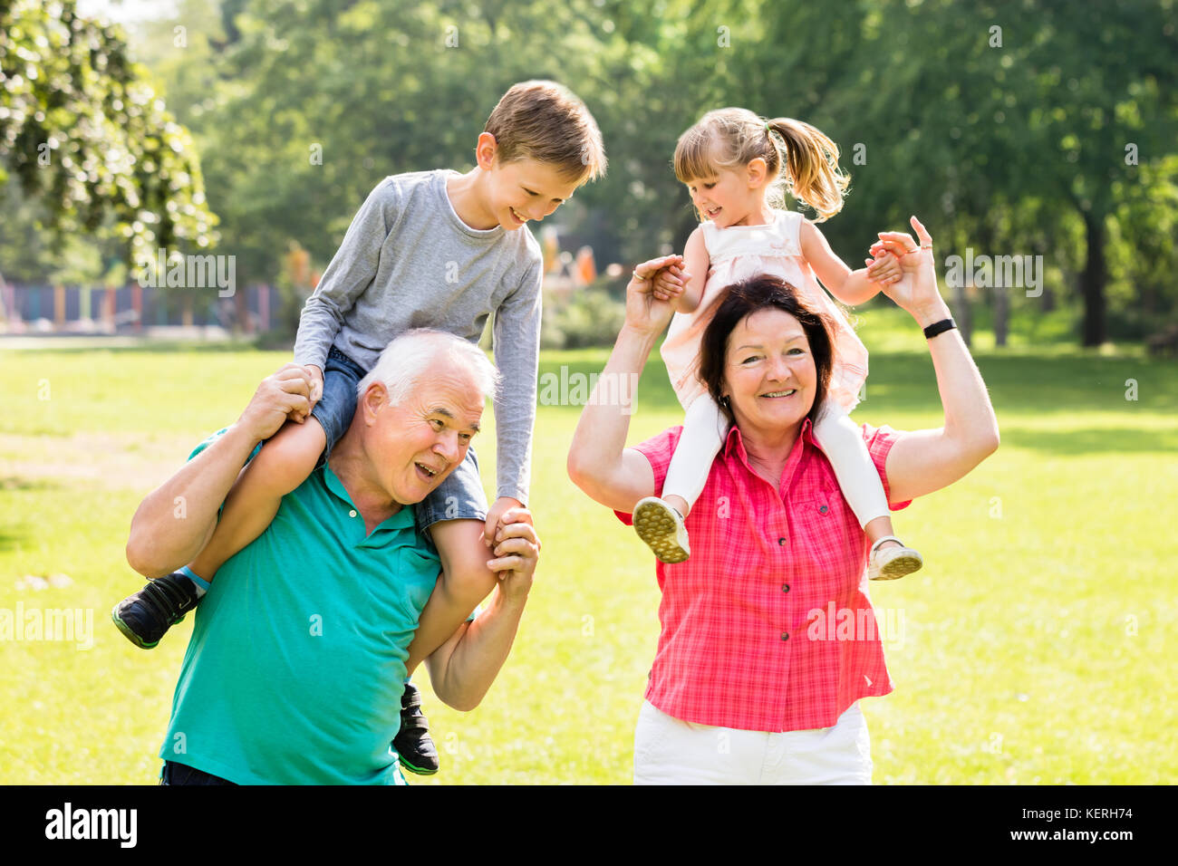 Heureux grands-parents de donner plaisir à leurs petits-enfants piggyback ride in park Banque D'Images
