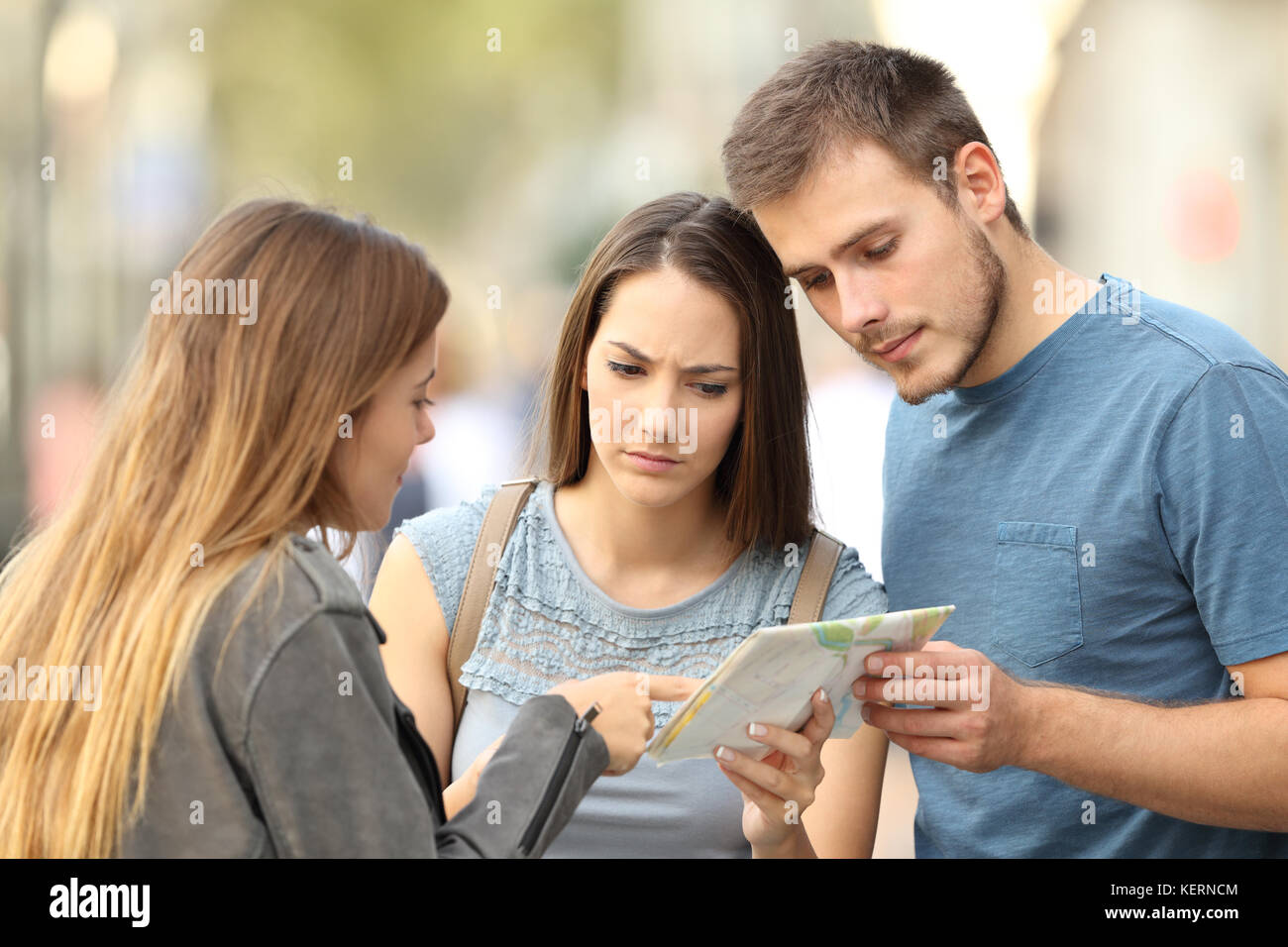 Girl contribuant à un couple de touristes à trouver un emplacement dans une carte papier sur la rue Banque D'Images