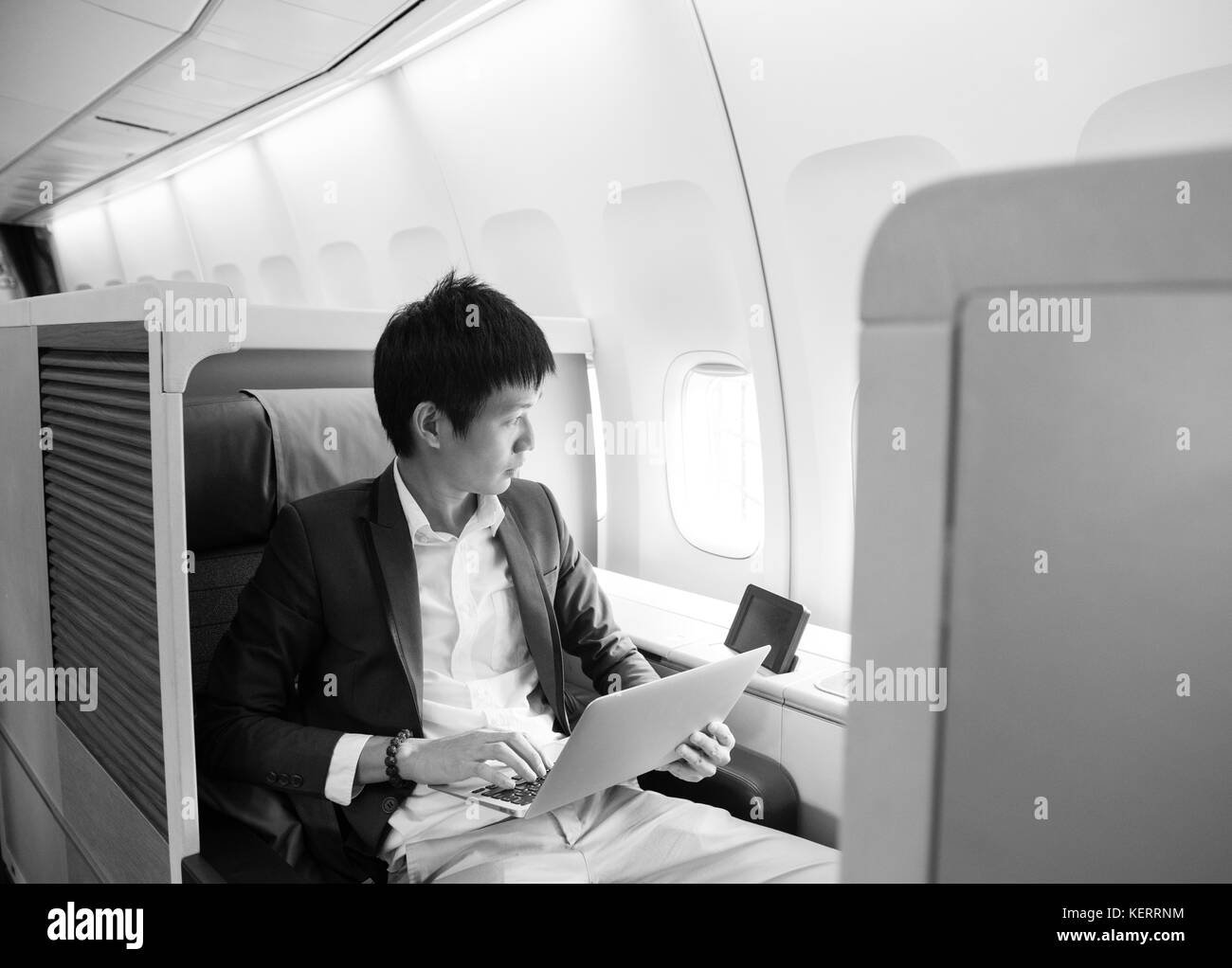 Asian businessman using laptop on cabine première classe Banque D'Images
