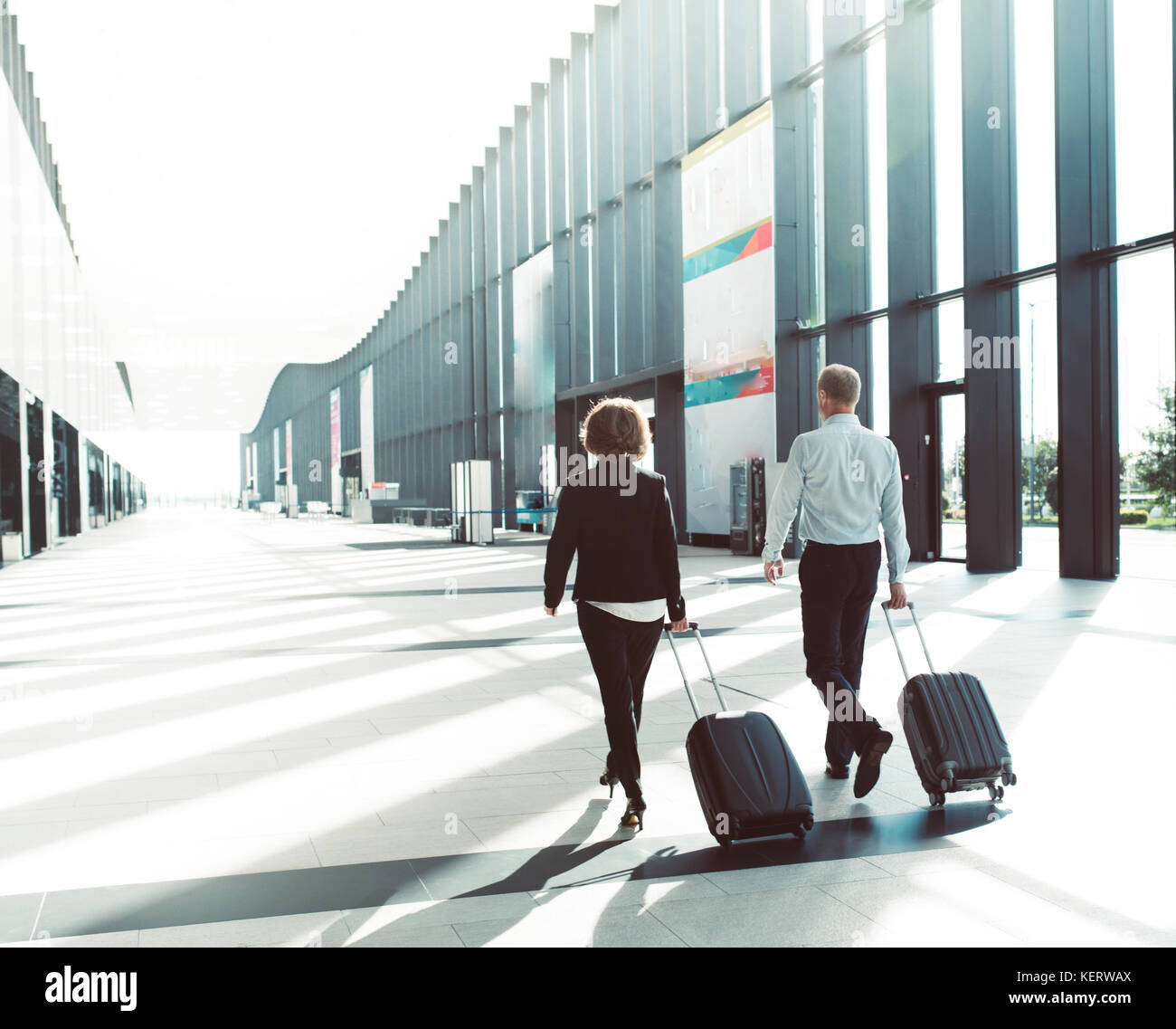 Les gens d'affaires dans l'Habillement formel walking in airport terminal avec des valises Banque D'Images